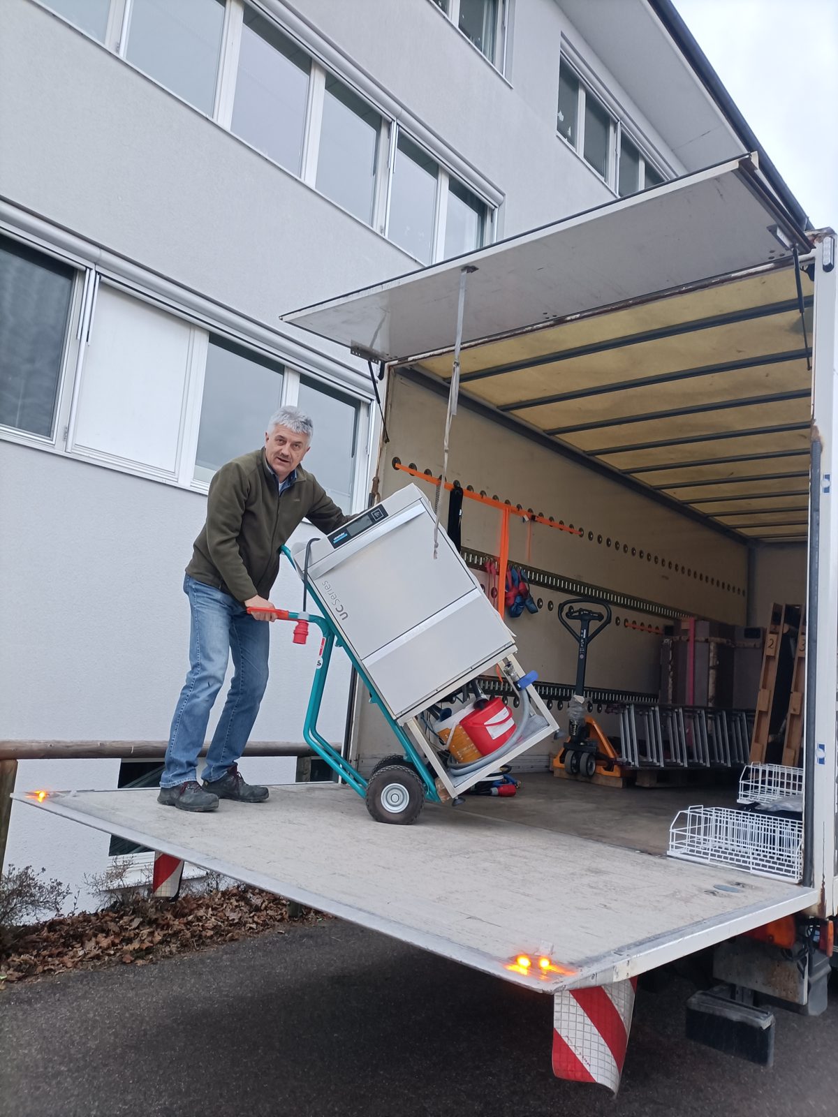 Sepp lädt einen Gläserspüler mit der Sackkarre auf die Ladebühne
